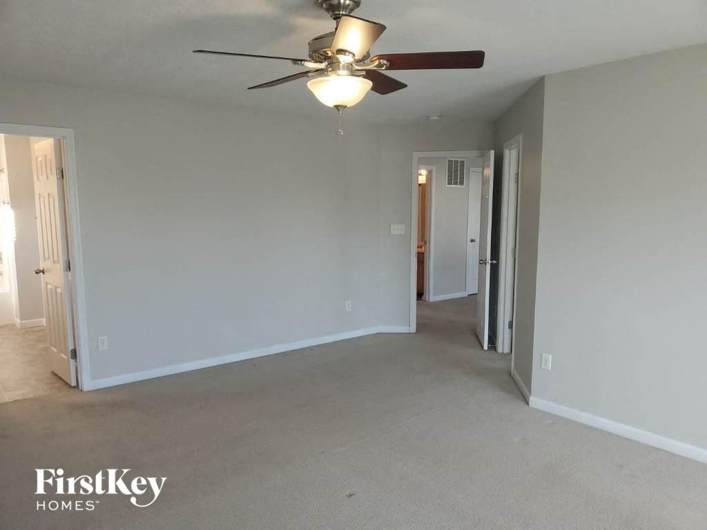 A spacious room with a ceiling fan and beige carpeting.