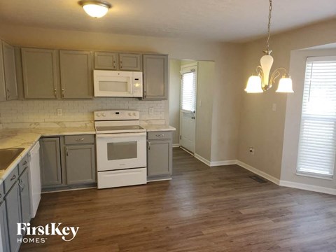 A kitchen with wooden floors and a white stove top oven.