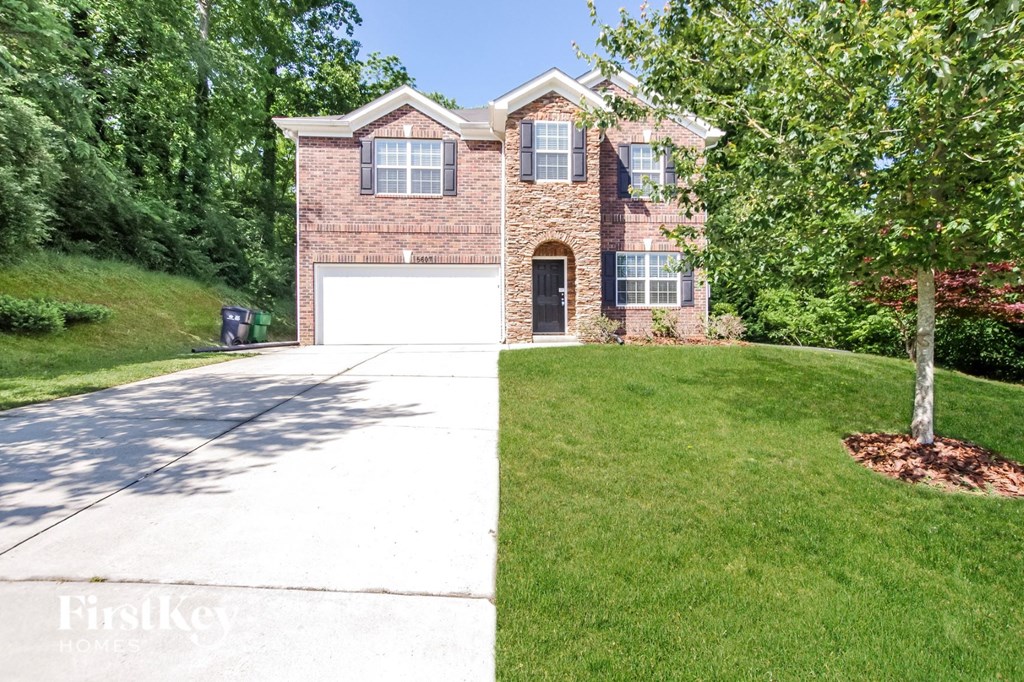 a brick house with a white garage door and a lawn