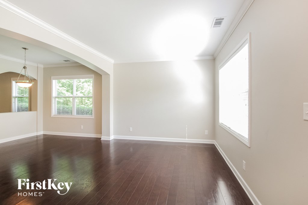 an empty living room with wood floors and a large window