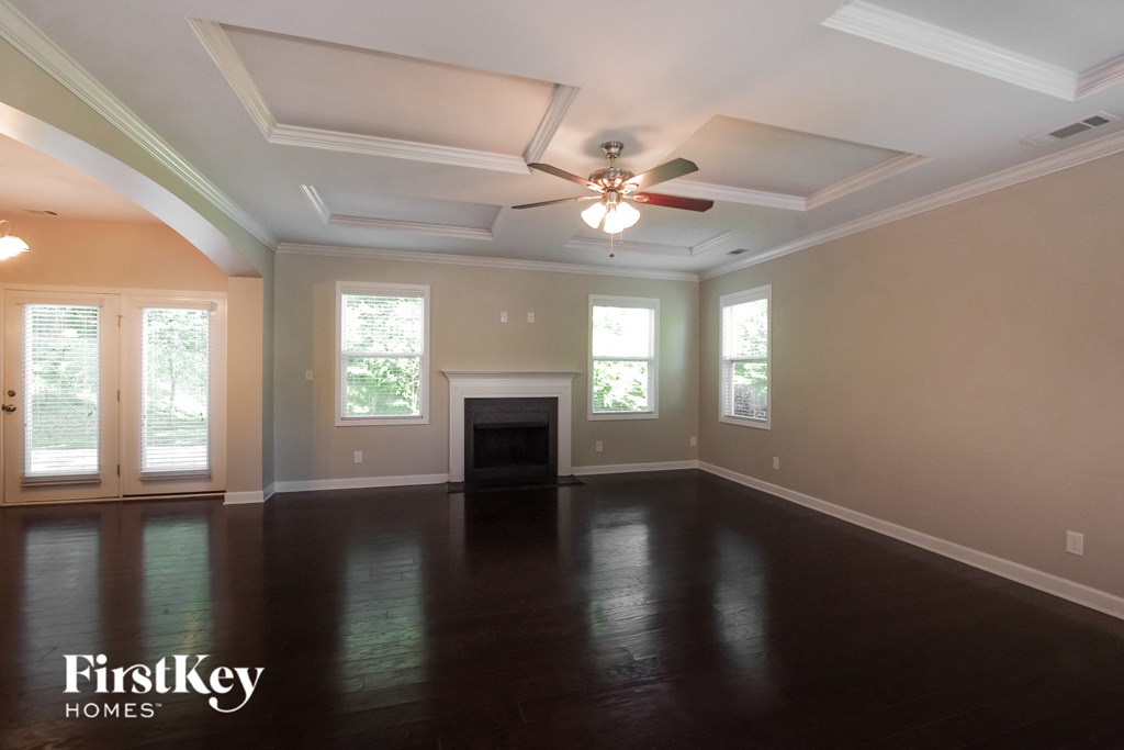 an empty living room with a ceiling fan and a fireplace