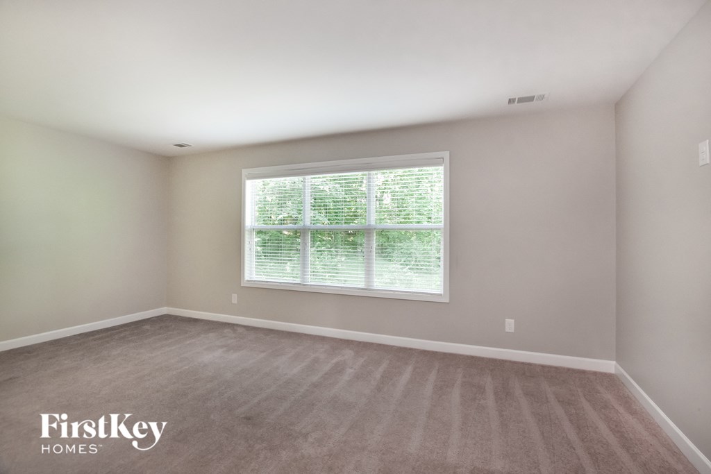 a bedroom with a large window and a carpeted floor