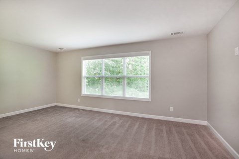 a bedroom with a large window and a carpeted floor