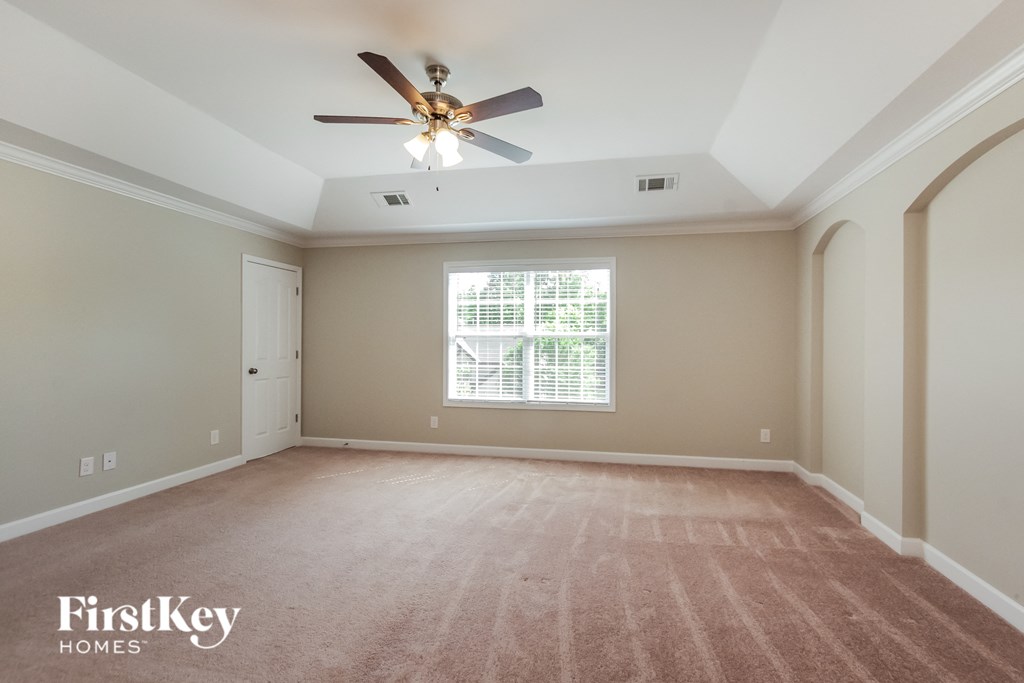 an empty living room with a ceiling fan and a window