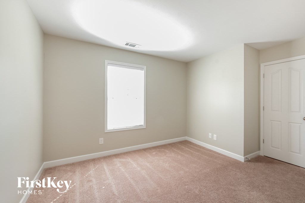 a bedroom with a carpeted floor and a window and white doors