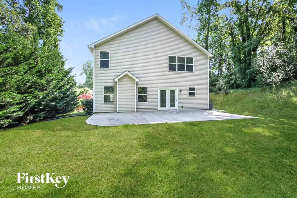 a white house with a concrete driveway and a lawn and trees