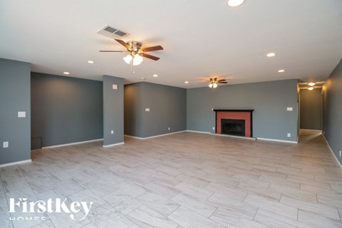 A spacious room with a fireplace and a ceiling fan.