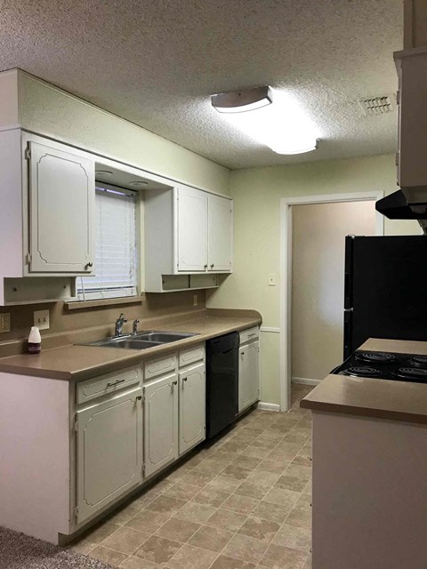 A kitchen with white cabinets and a black stove top oven.