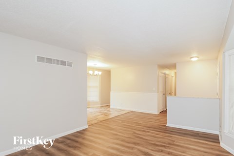 A spacious room with wooden flooring and white walls, with a doorway leading to another room.