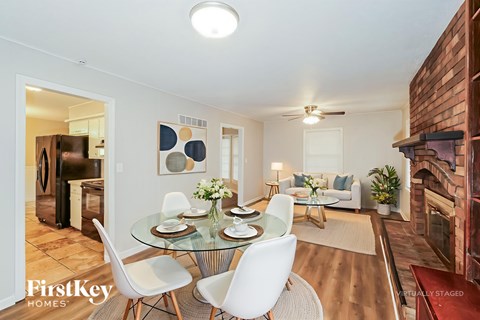 A dining room with a glass table and white chairs.