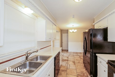 A kitchen with a black refrigerator and white cabinets.