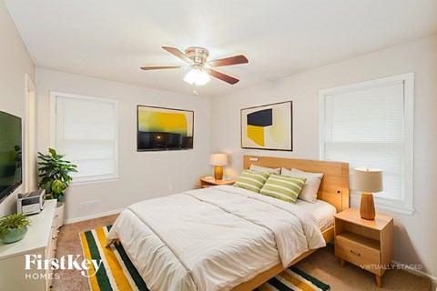 A bedroom with a bed, nightstand, and a ceiling fan.