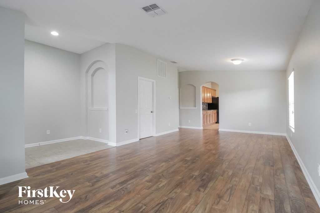 A spacious room with wooden flooring and white walls.
