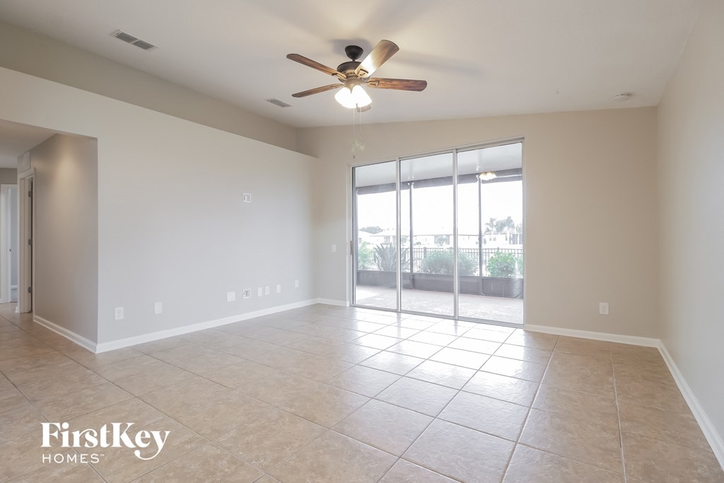 A spacious room with a ceiling fan and sliding glass doors leading to a balcony.