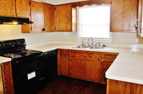 A kitchen with wooden cabinets and a black stove top oven.