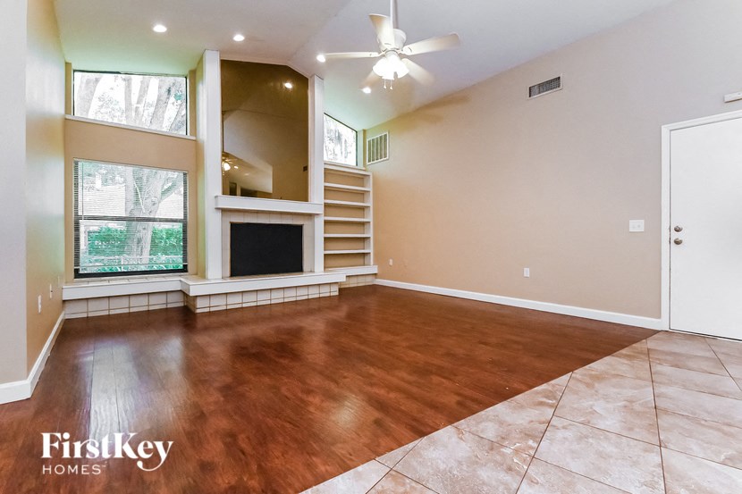 an empty living room with a fireplace and a ceiling fan
