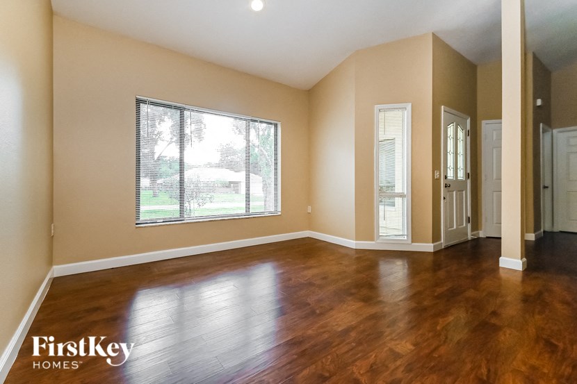 an empty living room with wood floors and a large window