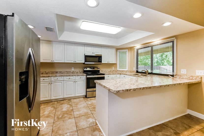 full kitchen with granite counter tops and white cabinets and stainless steel appliances