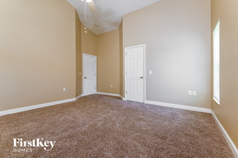 an empty living room with carpet and two doors