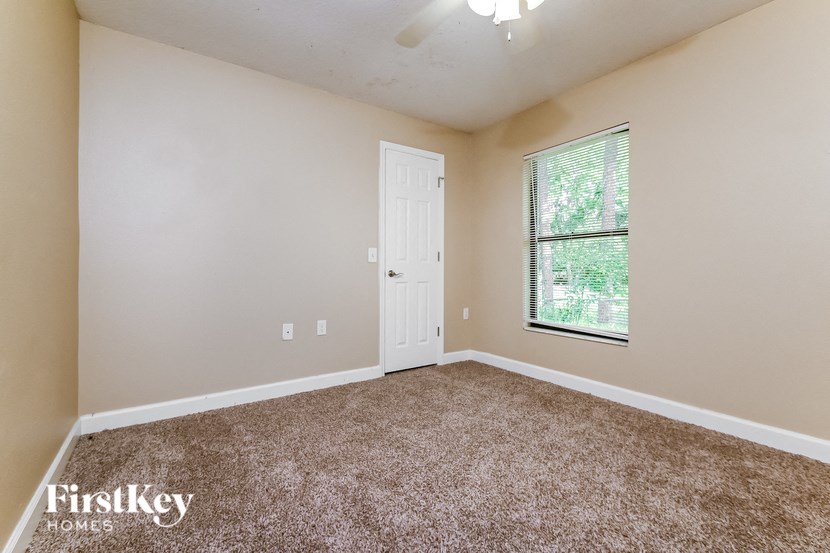 the spacious living room with carpeted flooring and a window