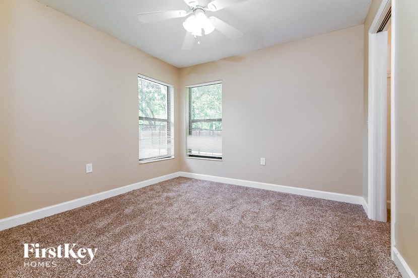 the spacious living room with carpeting and two windows