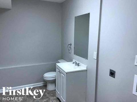A bathroom with a toilet, sink and mirror.