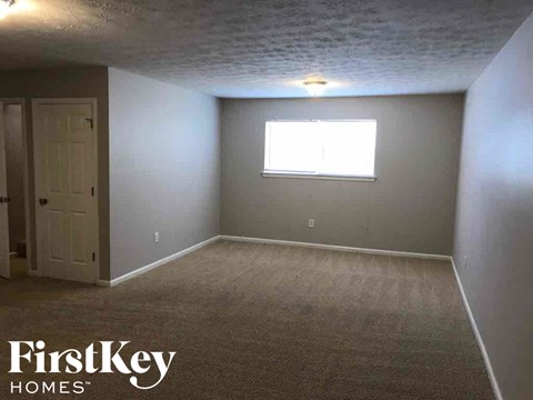 A room with a carpeted floor and a window with a white frame.