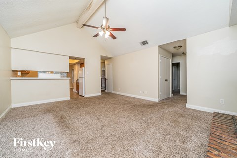 A spacious room with a ceiling fan and carpeted floor.