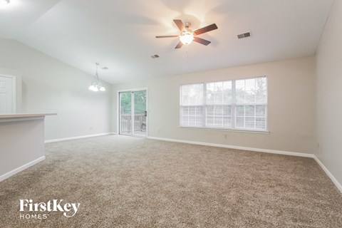 a spacious living room with carpet and a ceiling fan