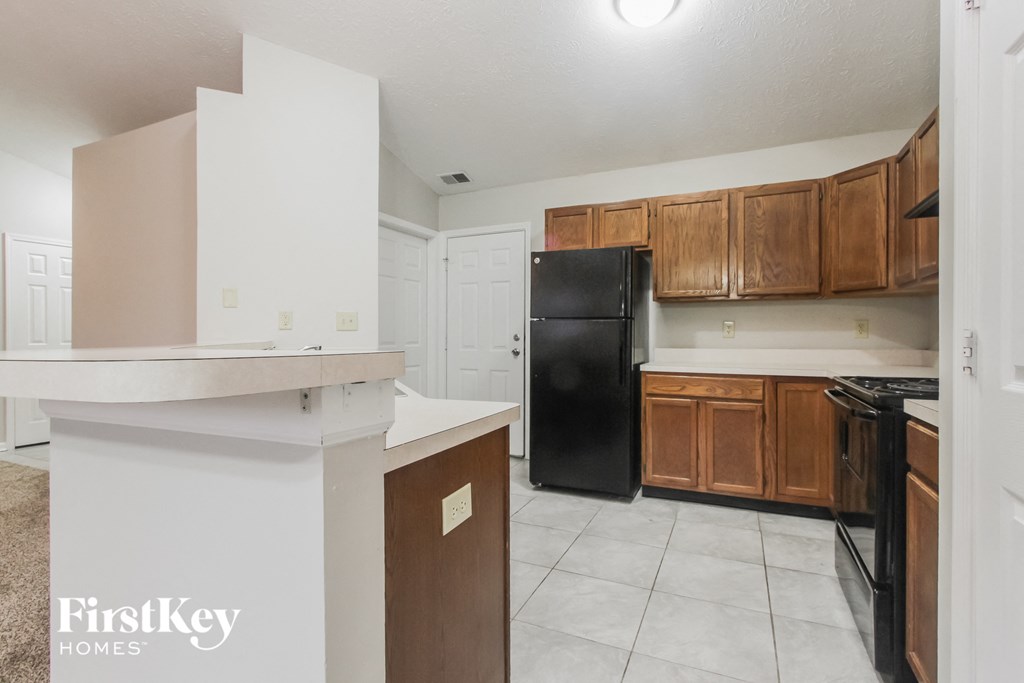 a kitchen with wooden cabinets and a black refrigerator