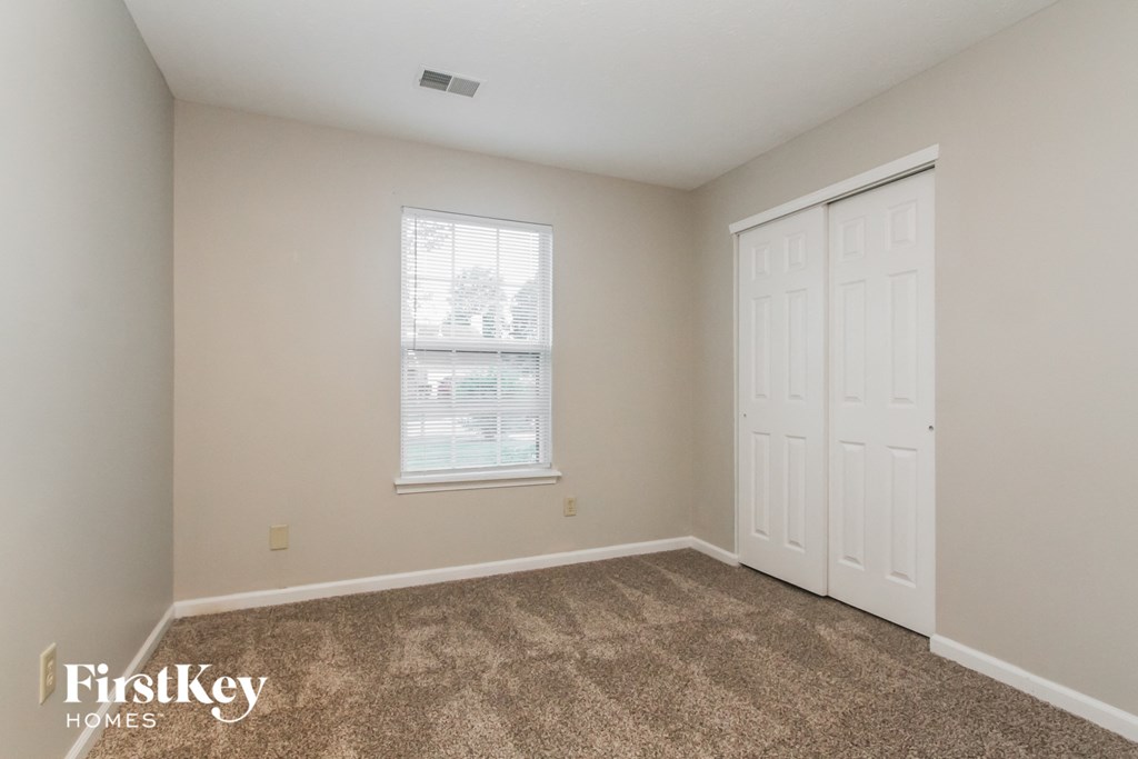 a bedroom with carpet and a white door and window