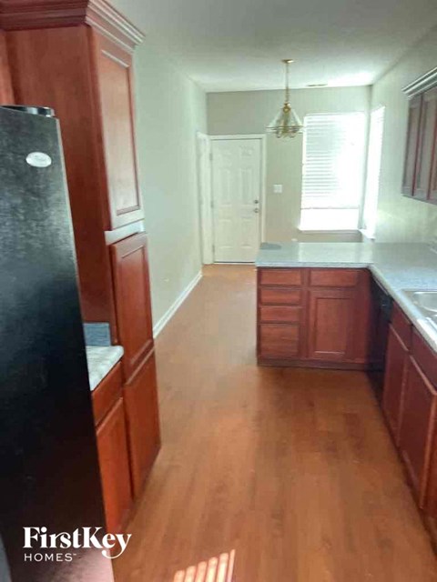 A kitchen with wooden cabinets and a black refrigerator.