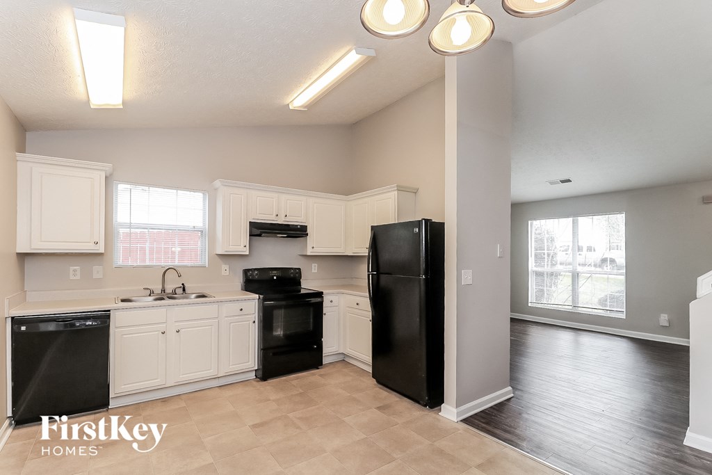 an empty kitchen with black appliances and white cabinets