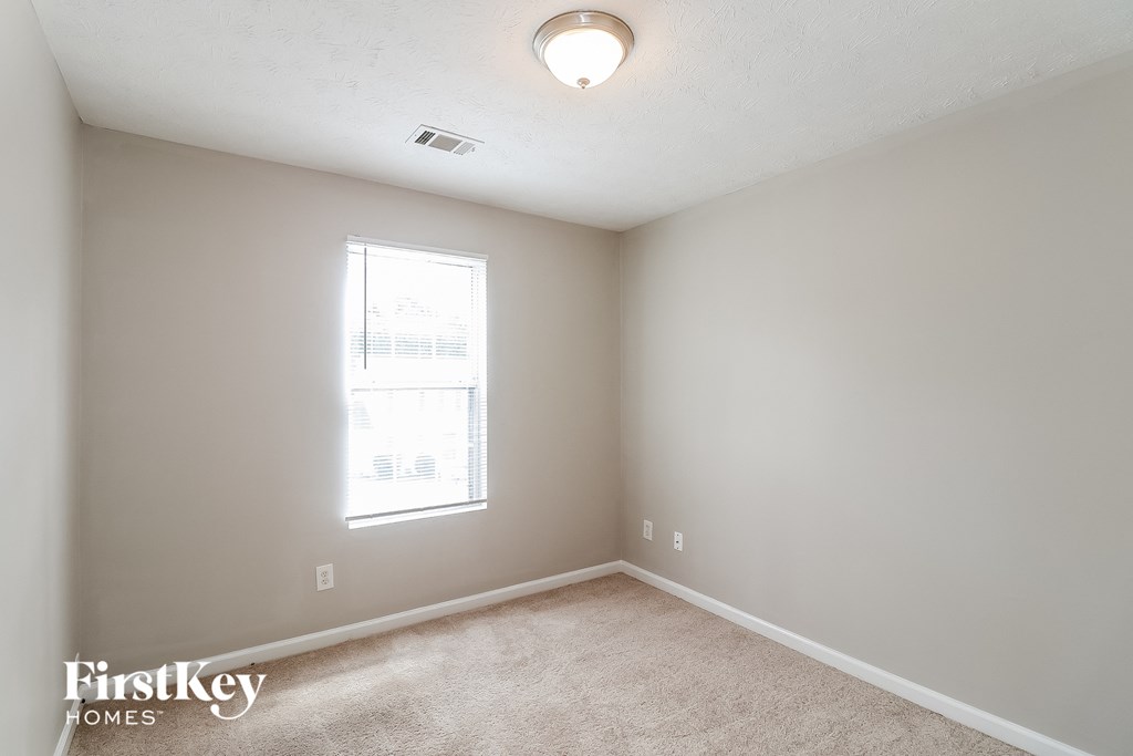 a bedroom with a window and a carpeted floor