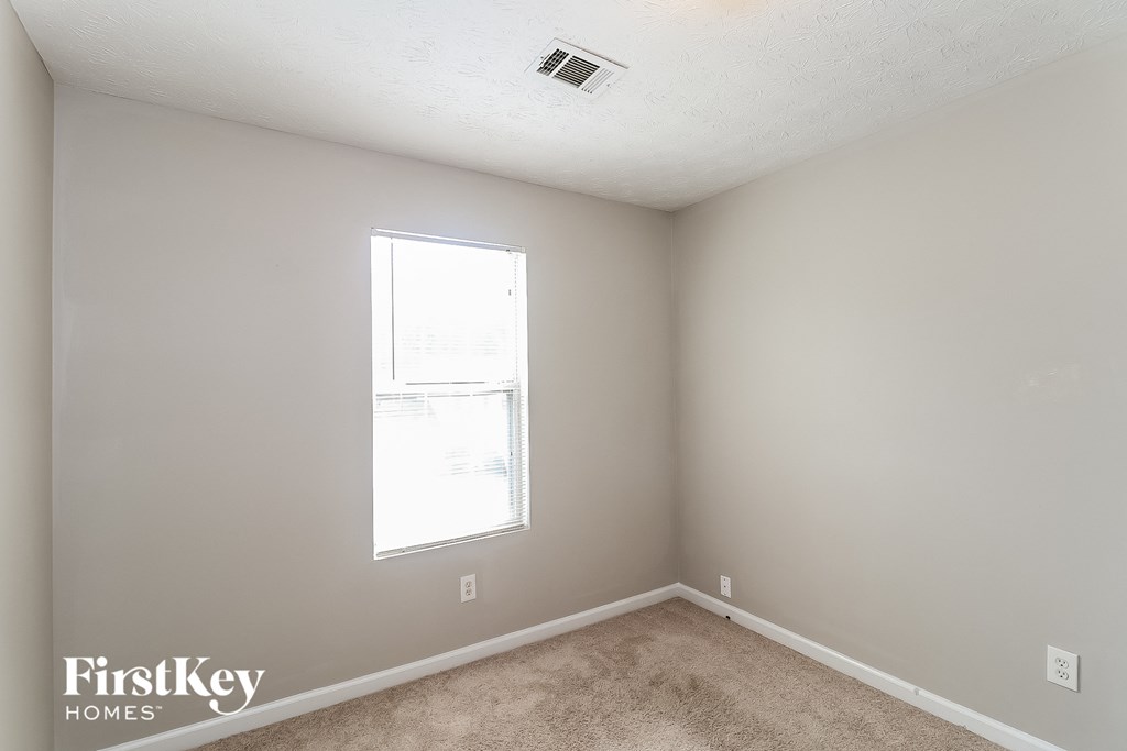 a bedroom with a window and a carpeted floor