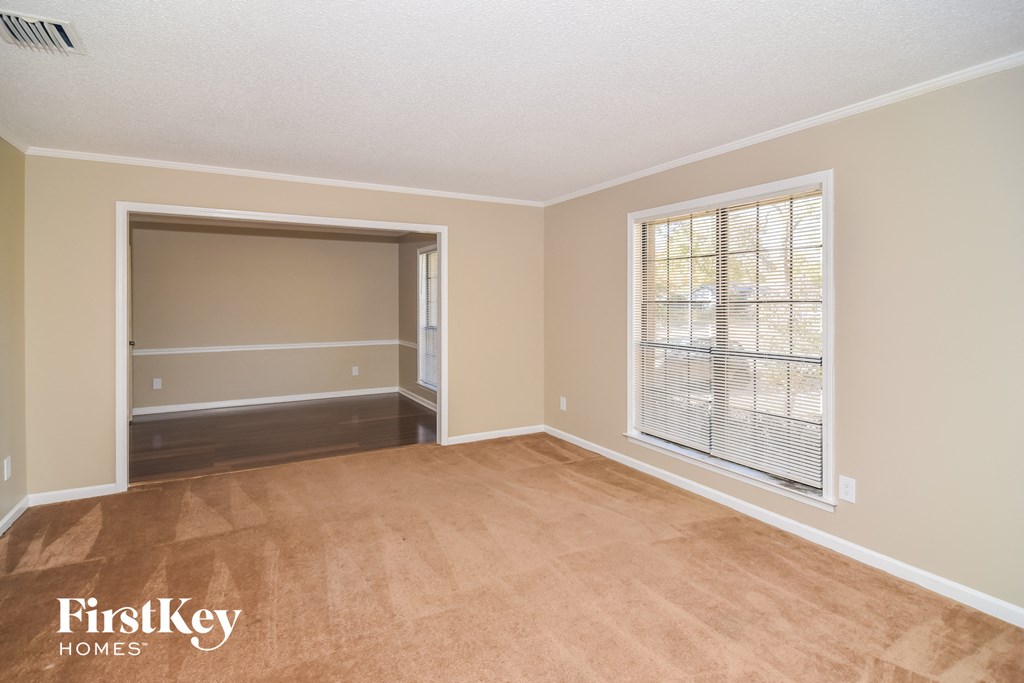 A room with a carpeted floor and a window with blinds.