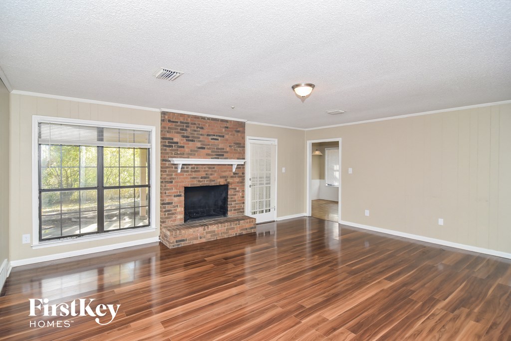 A living room with a fireplace and wood flooring.