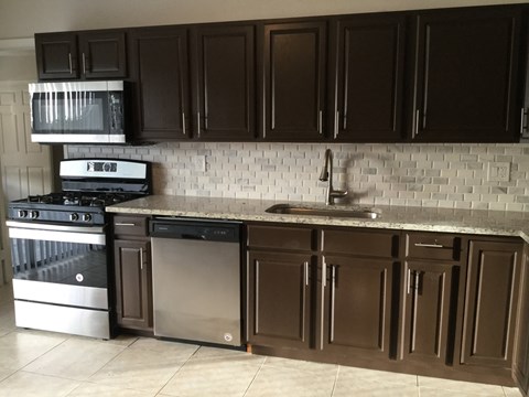A kitchen with brown cabinets and a white tile backsplash.