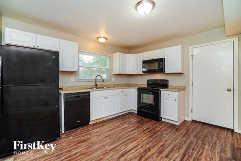 a kitchen with white cabinets and a black refrigerator