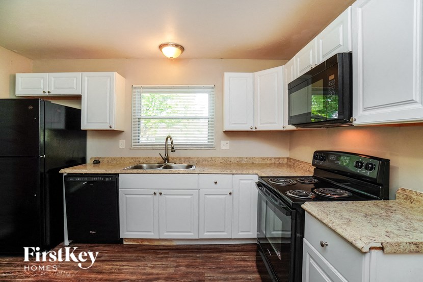 a kitchen with white cabinets and black appliances