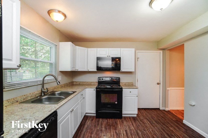 a kitchen with white cabinets and a sink and a stove