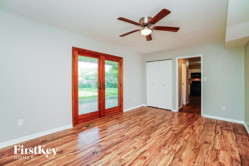an empty living room with wood floors and a ceiling fan