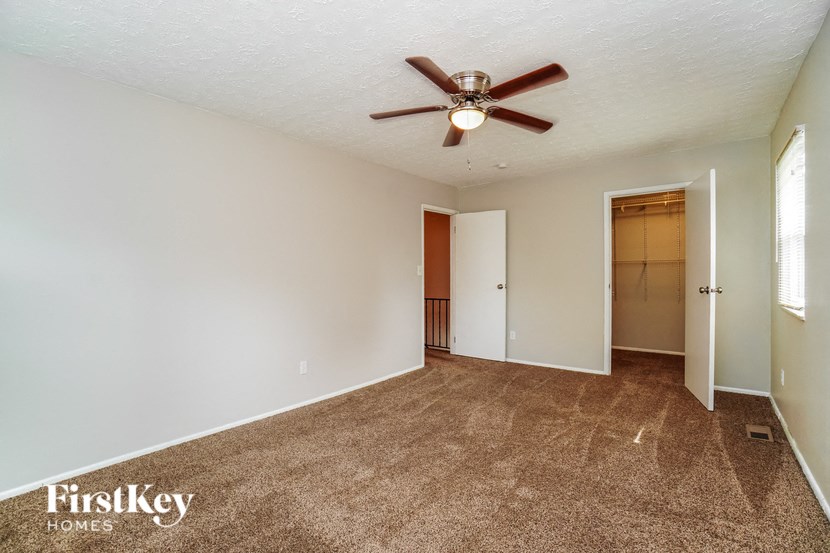 an empty living room with a ceiling fan and a closet
