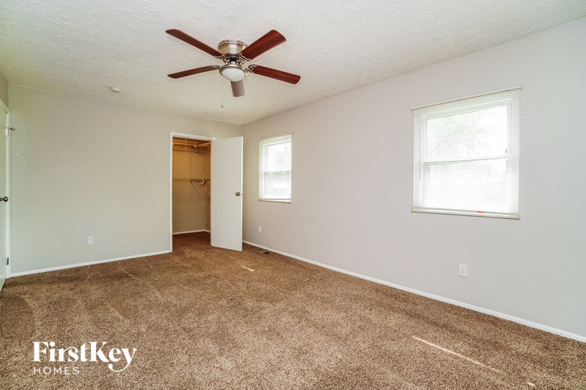 the master bedroom has carpeted floors and a ceiling fan