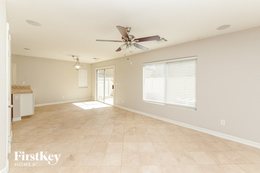 an empty living room with a ceiling fan and a window