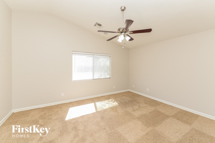 an empty living room with a ceiling fan and a window