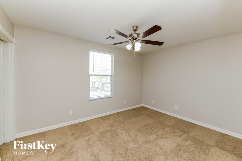an empty living room with a ceiling fan and a window