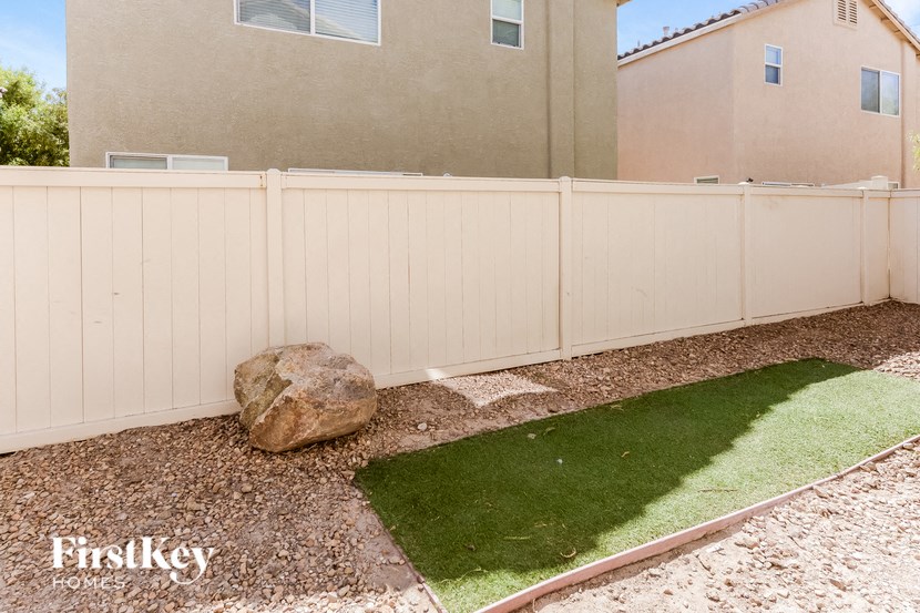 a white fence in a backyard with a rock and grass
