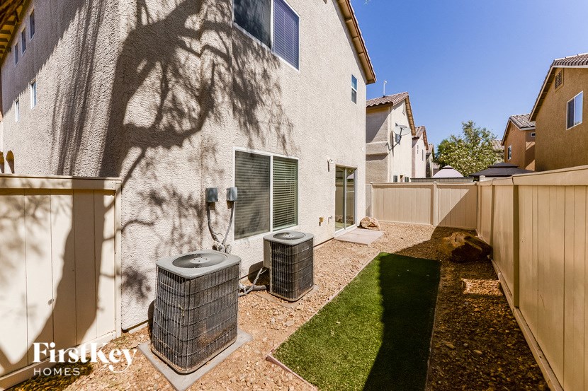 the backyard of a house with two fans in the yard