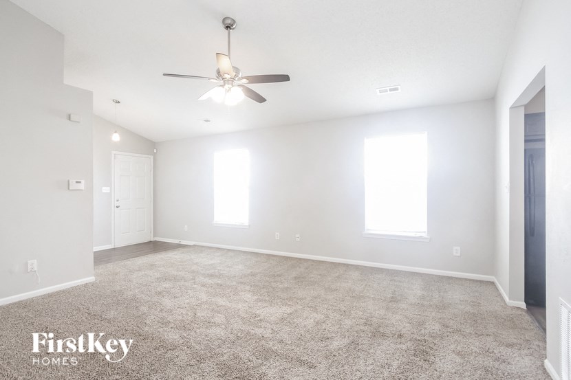 an empty living room with a ceiling fan
